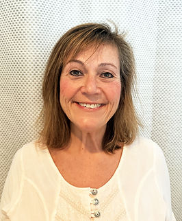 Smiling woman with shoulder-length brown hair wearing a white blouse, posed against a textured white background. Ideal for a professional profile or testimonial.